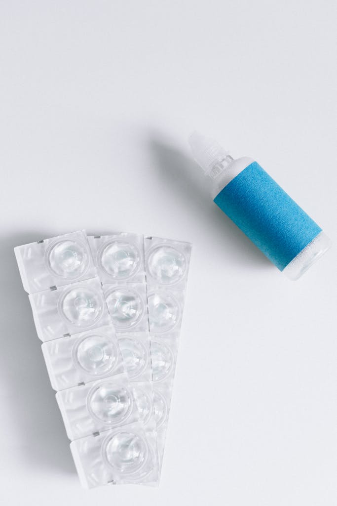 Flat lay image of contact lenses and solution bottle for eye care and optical use.